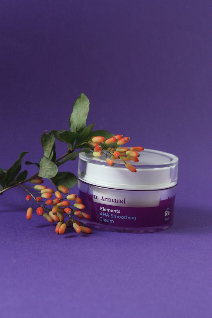 A close-up of AHA smoothing cream with colorful flowers on a vibrant purple background.